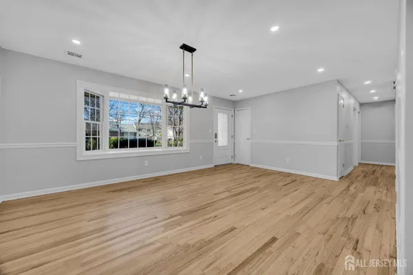 a view of a livingroom with wooden floor staircase and a kitchen space