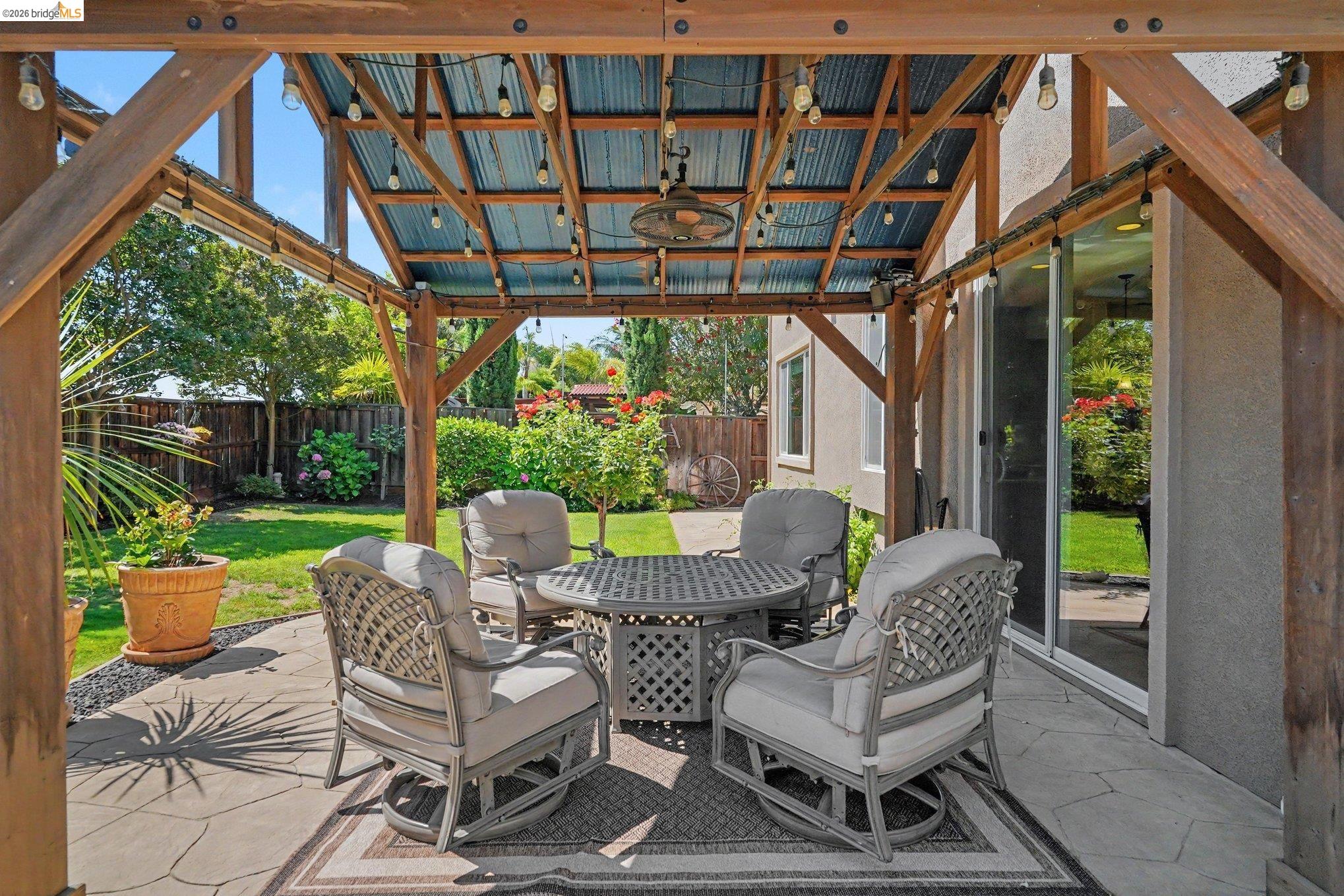 106 Little Ranch Circle Oakley, CA 94561 - Photo 26 of 34 Outdoor living space featuring a wood-frame patio cover with corrugated metal roofing, string lighting, and an overhead fan