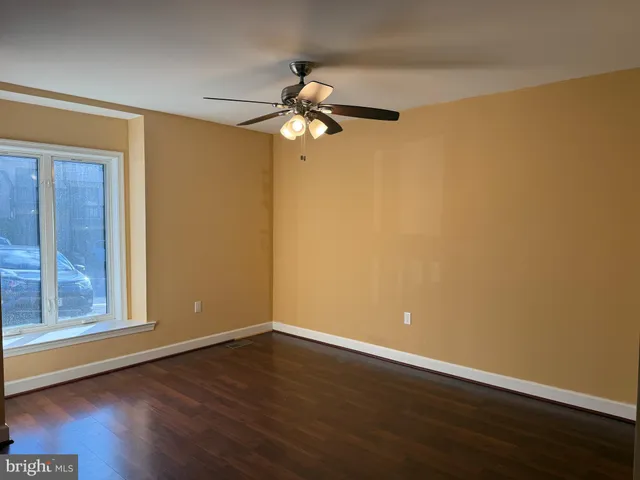 a view of a room with wooden floor fan and windows