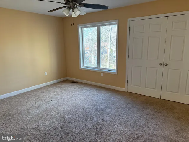 an empty room with a window and a ceiling fan