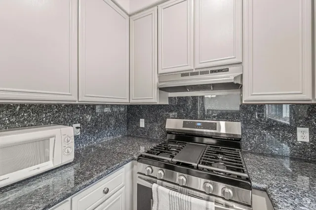 a kitchen with granite countertop white cabinets and stainless steel appliances
