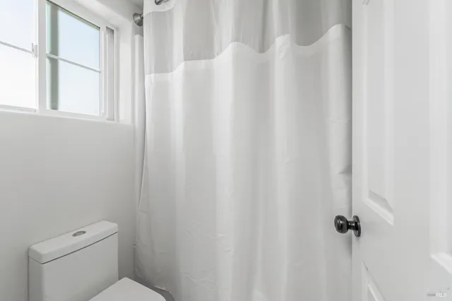 a white toilet sitting next to a shower