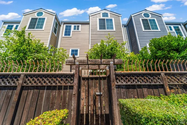 a view of a brick house with wooden fence and plants