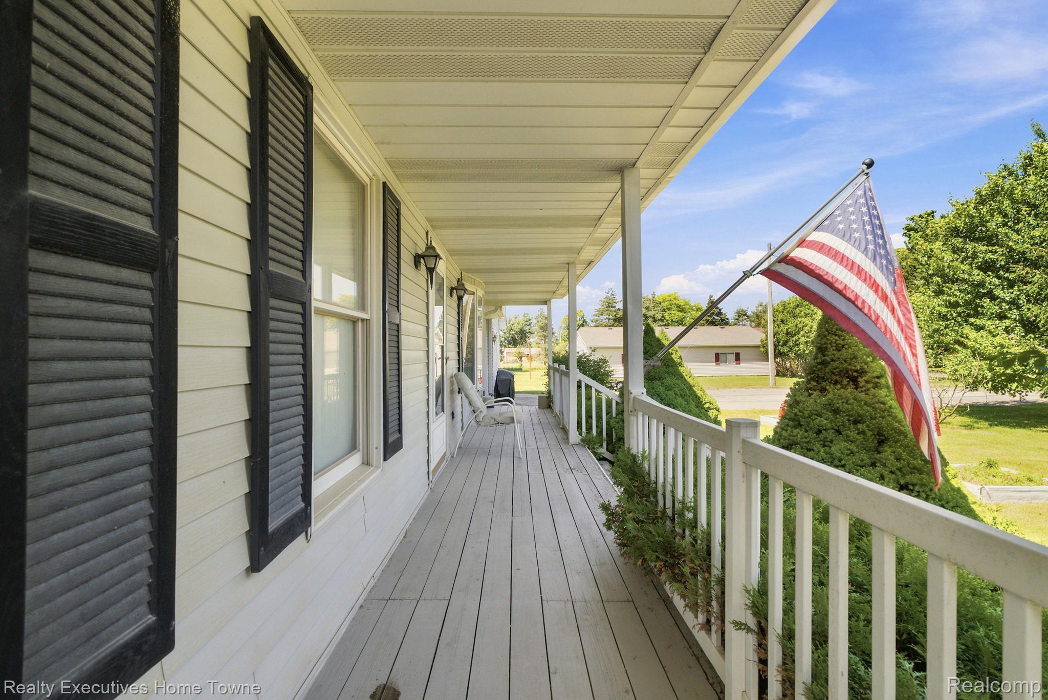 959 Braidwood Road Memphis, MI 48041 - Photo 13 of 58 Expansive covered front porch with composite decking, white railing, and exterior wall lanterns