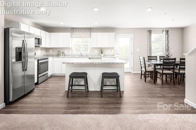 117 Hackamore Road, Unit 208 Troutman, NC 28166 - Photo 3 of 17 a kitchen with stainless steel appliances granite countertop a table chairs microwave and sink