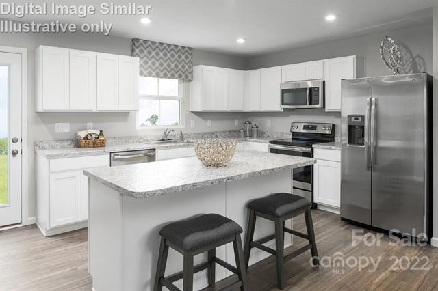 117 Hackamore Road, Unit 208 Troutman, NC 28166 - Photo 5 of 17 a kitchen with stainless steel appliances granite countertop a white cabinets and a refrigerator
