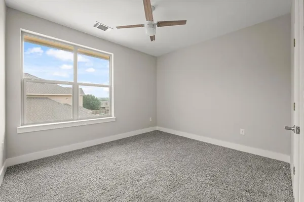 an empty room with windows and ceiling fan