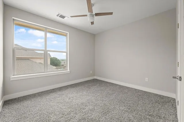 an empty room with windows and ceiling fan