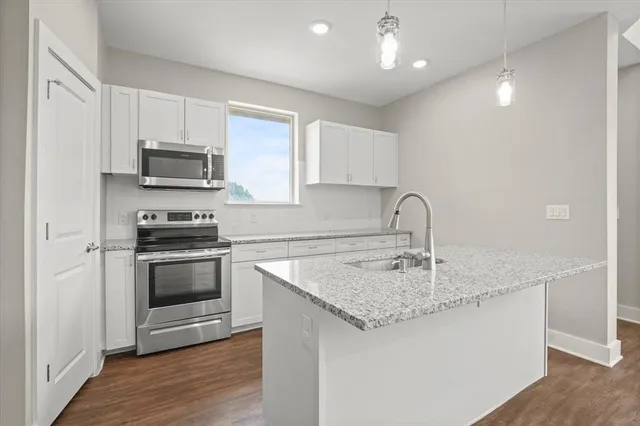 a view of kitchen with kitchen island wooden floor and stainless steel appliances