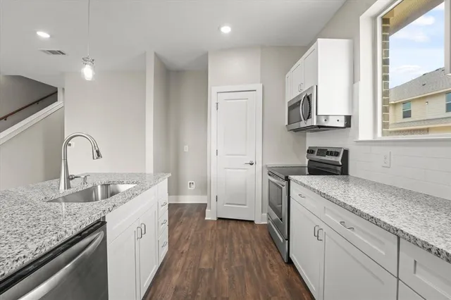 a view of kitchen with kitchen island stainless steel appliances cabinets and wooden floor