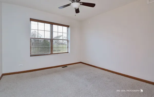 an empty room with ceiling fan and windows