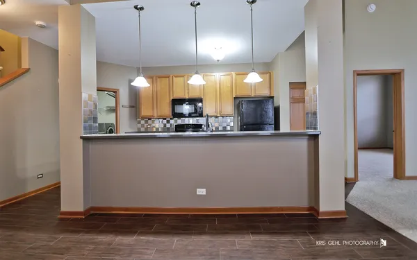 a view of a kitchen with kitchen island a sink stainless steel appliances and cabinets