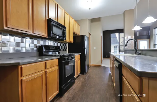 a kitchen with stainless steel appliances granite countertop a sink a stove a refrigerator cabinets and a wooden floor