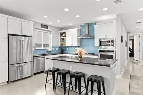 a kitchen with stainless steel appliances granite countertop a refrigerator and a stove top oven