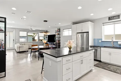 a kitchen with stainless steel appliances granite countertop a refrigerator a sink dishwasher a dining table and chairs with wooden floor