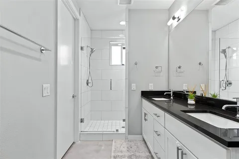 a bathroom with a double vanity sink a large mirror and shower