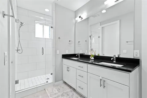 a bathroom with double sink and a shower