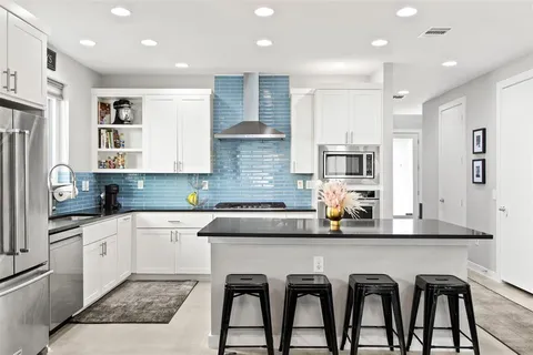 a kitchen with stainless steel appliances granite countertop a table chairs sink and cabinets