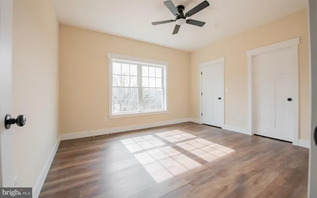 a view of empty room with wooden floor and fan