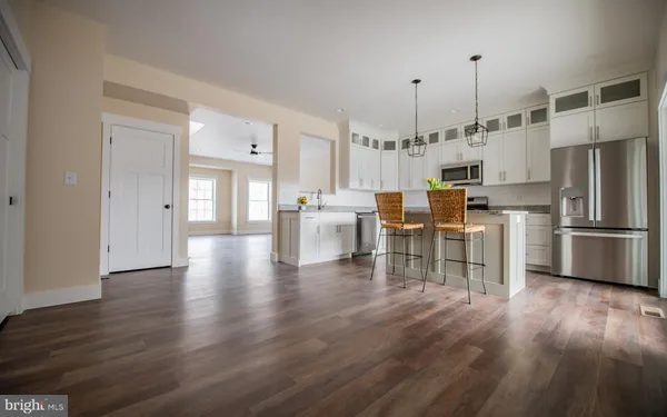a kitchen with stainless steel appliances a refrigerator a stove microwave and a dining table with wooden floor