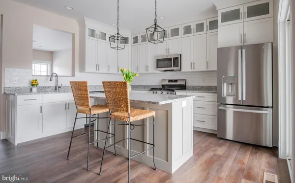 a kitchen with stainless steel appliances a refrigerator a stove a sink dishwasher and white cabinets with wooden floor