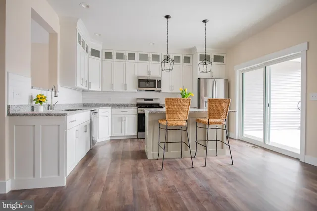 a kitchen with stainless steel appliances a white table chairs and a refrigerator