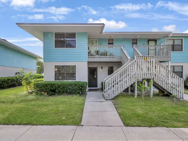 a view of house with a yard and potted plants