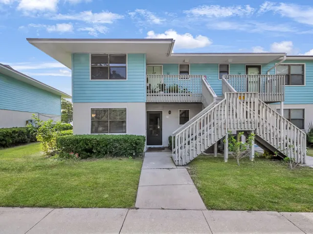 a view of house with a yard and potted plants
