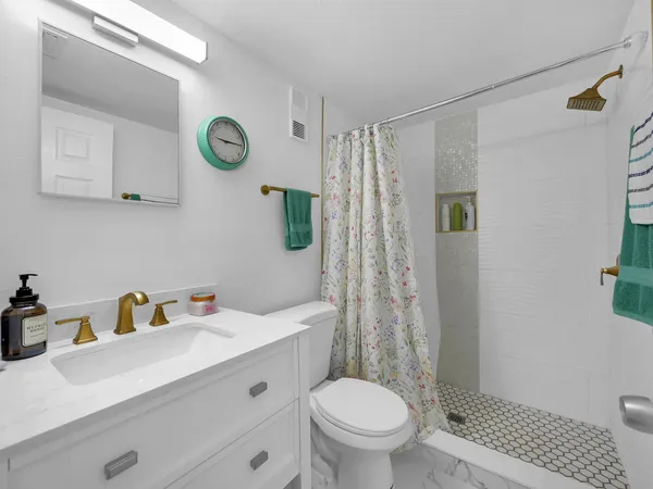 a view of a hallway with wooden floor and a bathroom