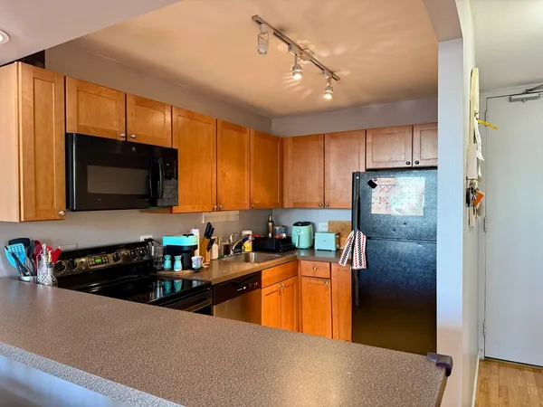 a kitchen with stainless steel appliances granite countertop a refrigerator a stove and a sink with wooden floor