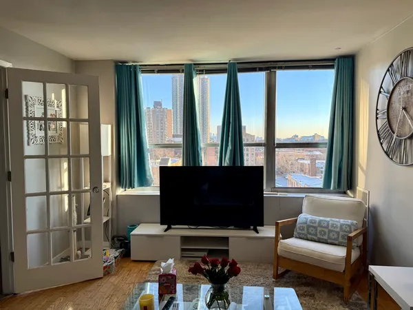 a living room with furniture a flat screen tv and a floor to ceiling window