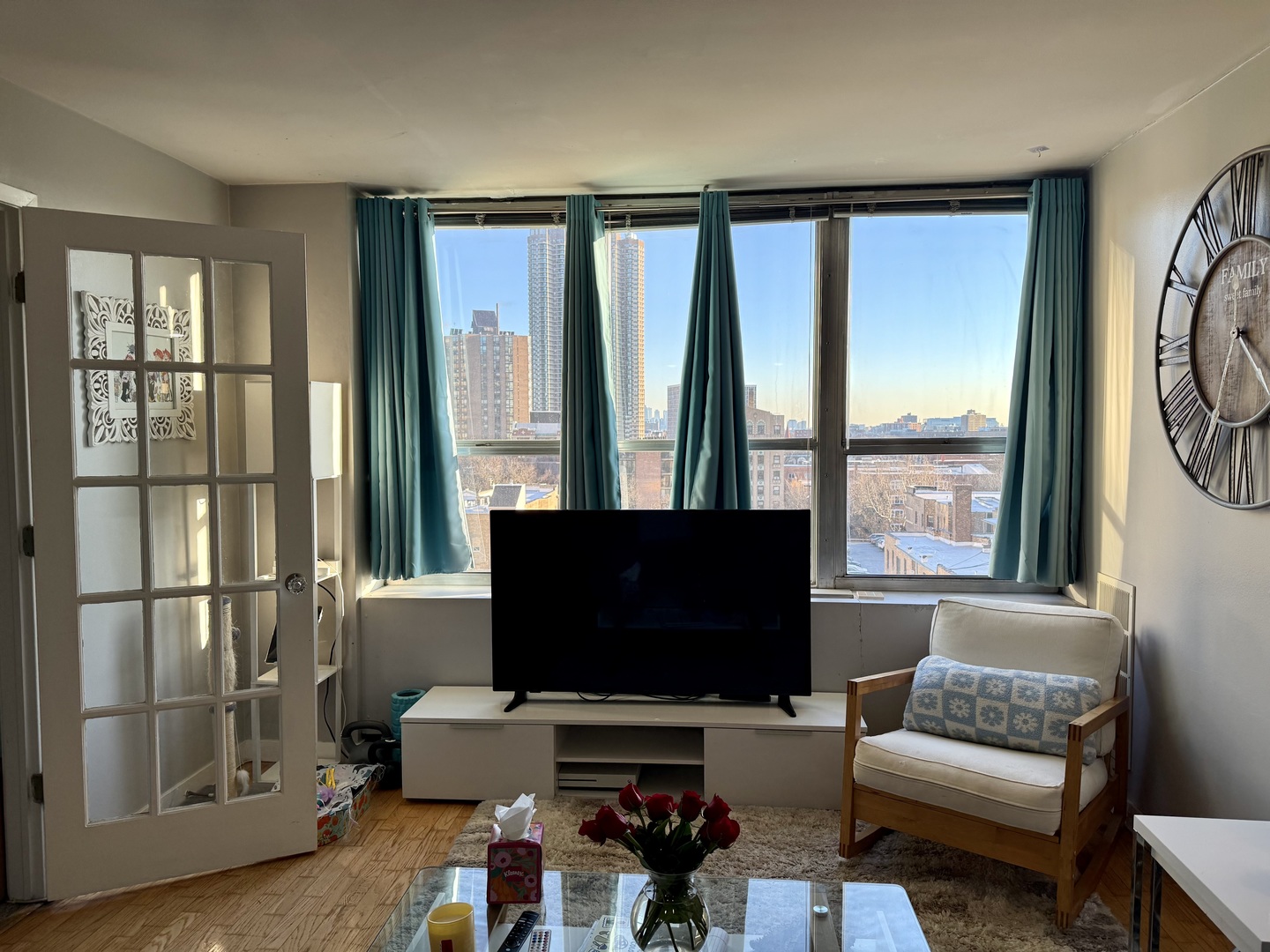655 West Irving Park Road, Unit 707 Chicago, IL 60613 - Photo 6 of 13 a living room with furniture a flat screen tv and a floor to ceiling window