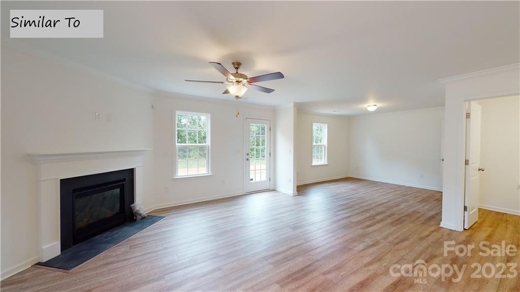 1118 Baileys Chapel Road Advance, NC 27006 - Photo 5 of 10 an empty room with wooden floor fireplace and windows