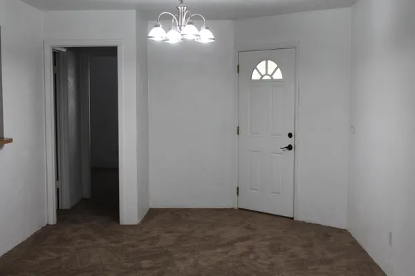 an empty room with a chandelier fan and a bathroom