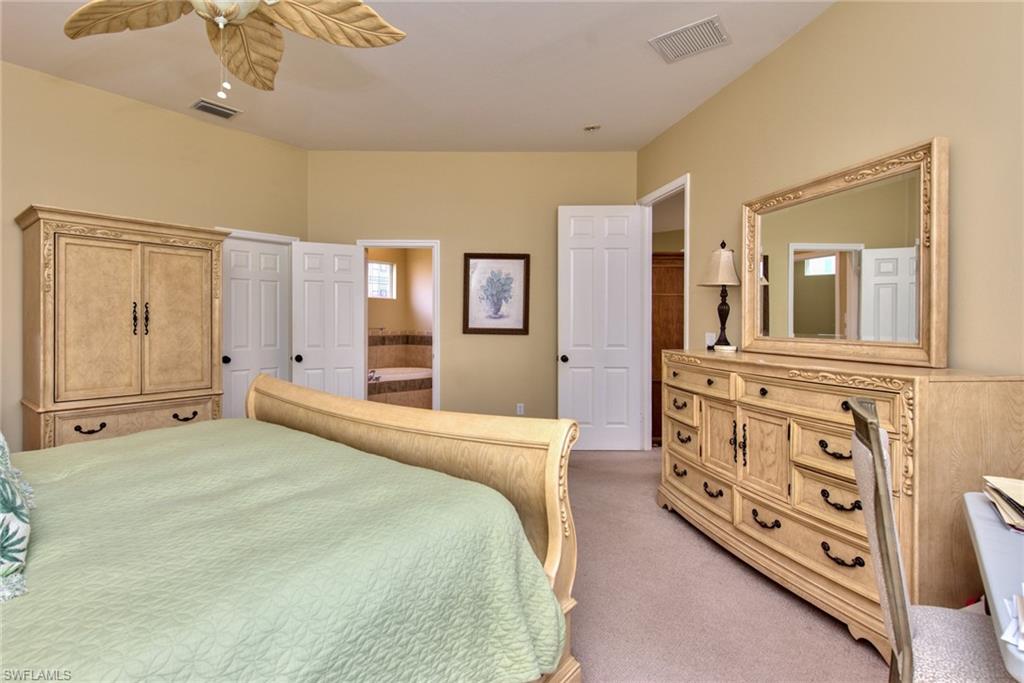 3748 Kent Drive Naples, FL 34112 - Photo 23 of 30 a spacious bedroom with a bed a dresser and mirror