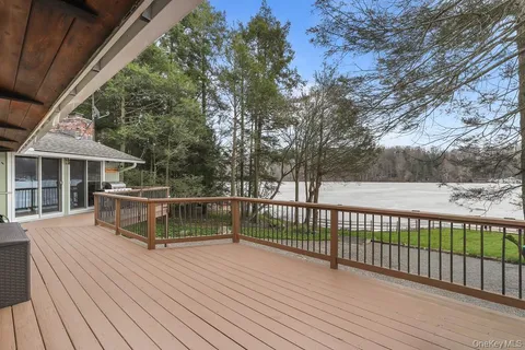a view of house with deck outdoor seating and covered with trees