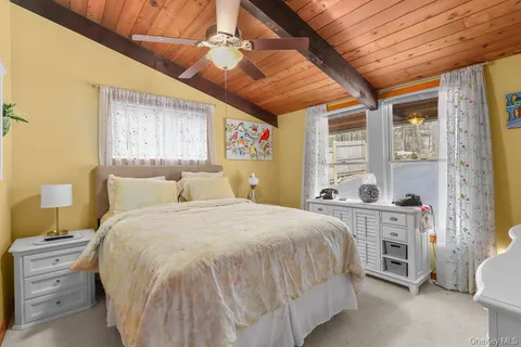 a spacious bedroom with a bed a dresser next to a window