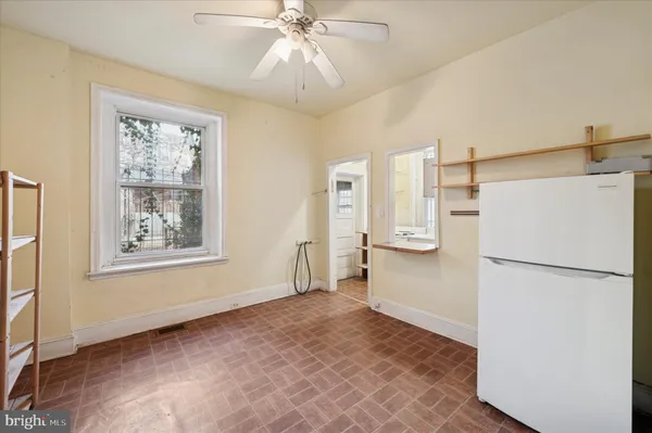a view of a kitchen with a refrigerator cabinet a ceiling fan and a window