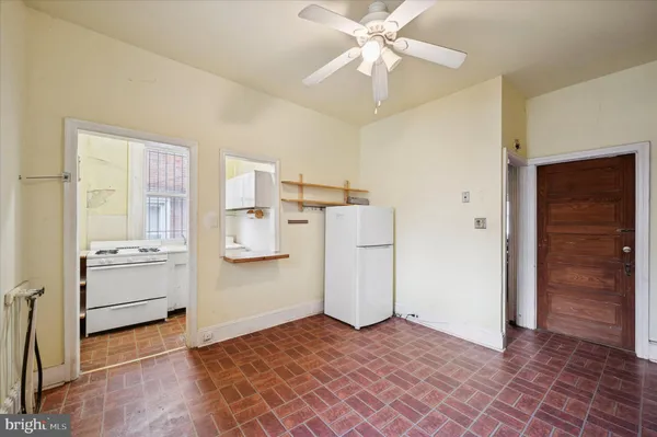 a view of a livingroom with a chandelier fan and kitchen space with a stove top oven