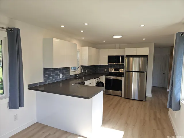 a kitchen with stainless steel appliances granite countertop a refrigerator a sink a stove and oven with wooden floor