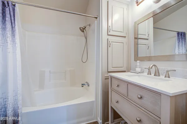a bathroom with a granite countertop sink a mirror a vanity and a bathtub
