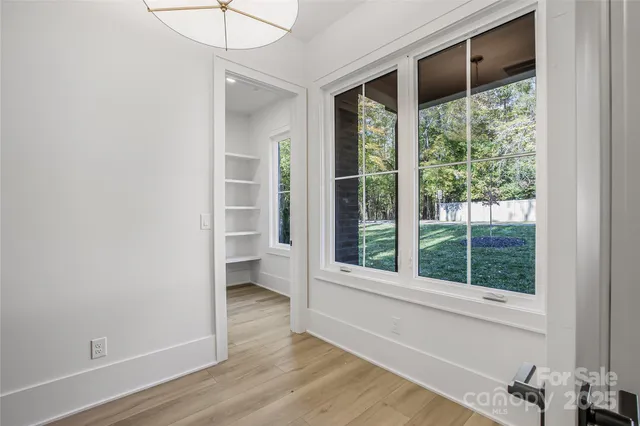 a view of an empty room with a window and wooden floor