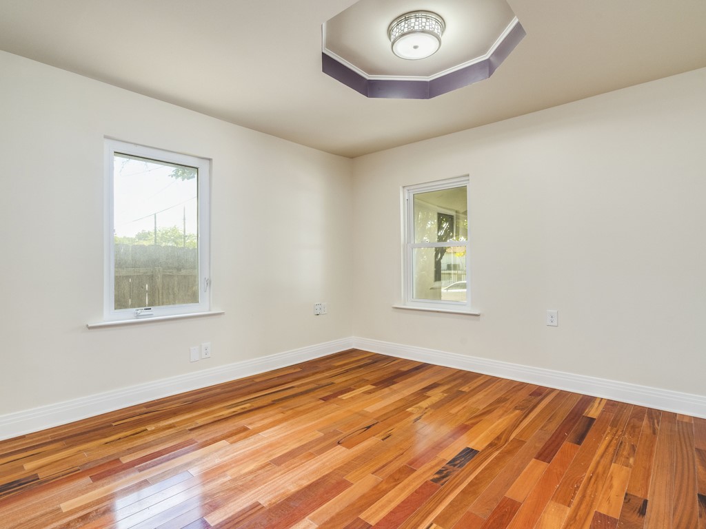 2314 Santa Rosa Street Austin, TX 78702 - Photo 9 of 27 Unfurnished room featuring light wood-style floors, healthy amount of natural light, and a tray ceiling