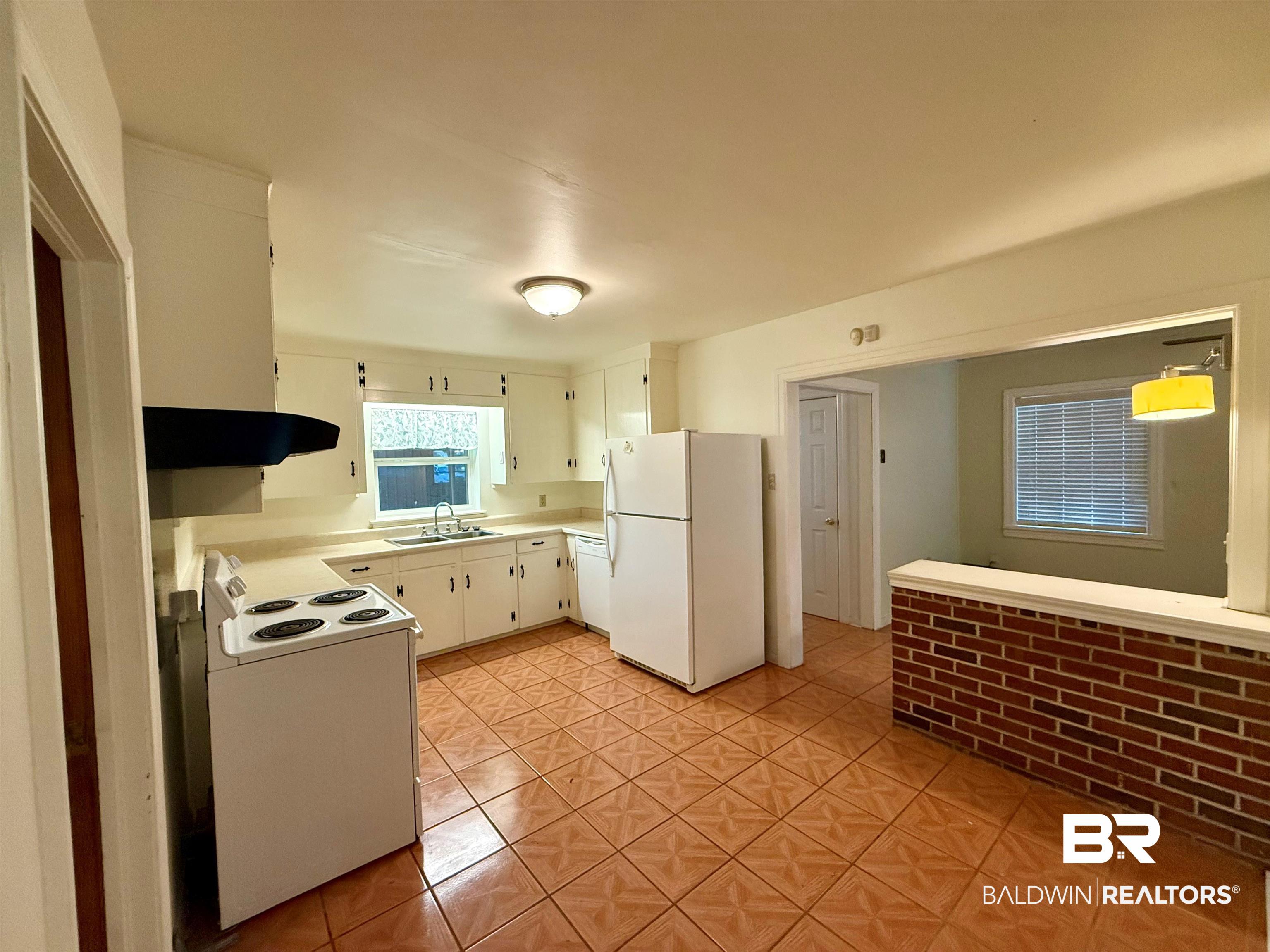 403 Sutherland Drive Mobile, AL 36611 - Photo 3 of 8 Kitchen with white appliances, under cabinet range hood, a sink, light countertops, and light tile patterned floors