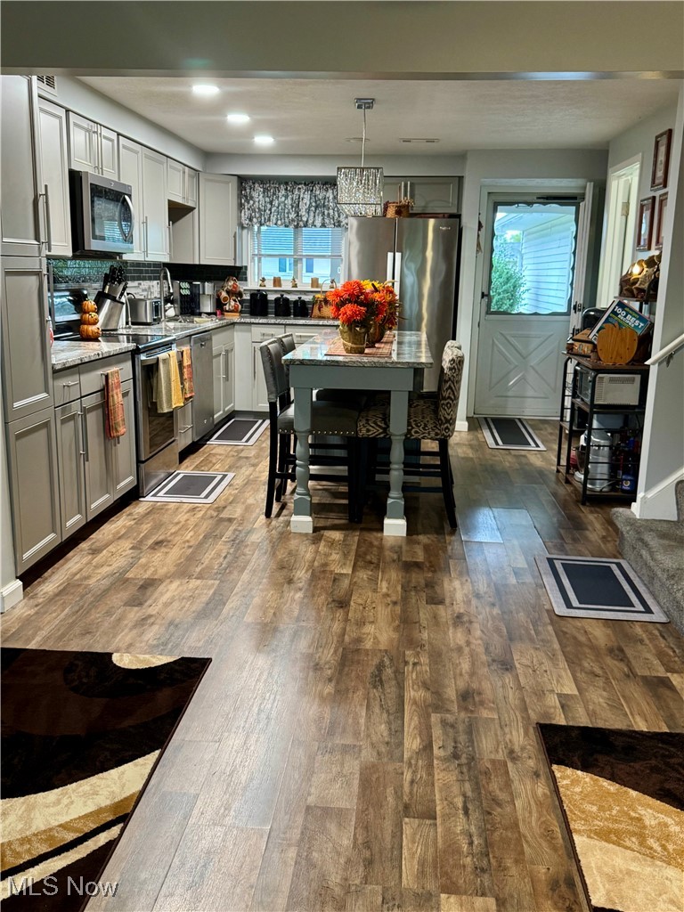8949 West Ridge Road, Unit B Elyria, OH 44035 - Photo 6 of 24 Kitchen with appliances with stainless steel finishes, dark wood-type flooring, pendant lighting, gray cabinetry, and light stone counters
