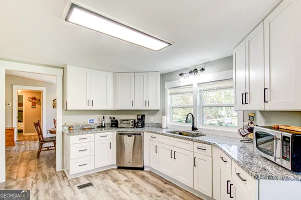 a kitchen with granite countertop a sink window and stainless steel appliances