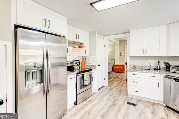 a kitchen with white cabinets and stainless steel appliances