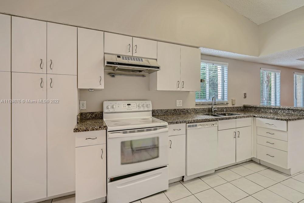 23060 Aqua, Unit 8 Boca Raton, FL 33433 - Photo 22 of 33 a kitchen with granite countertop white cabinets and white appliances