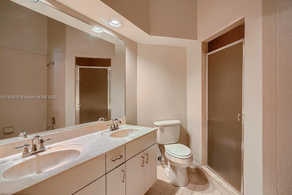 23060 Aqua, Unit 8 Boca Raton, FL 33433 - Photo 8 of 33 a bathroom with a granite countertop toilet a sink and a mirror