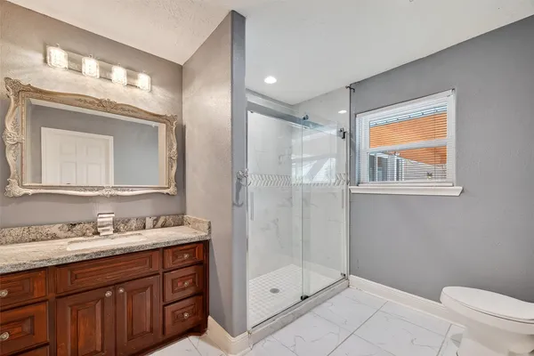 a bathroom with a granite countertop sink toilet a mirror and shower